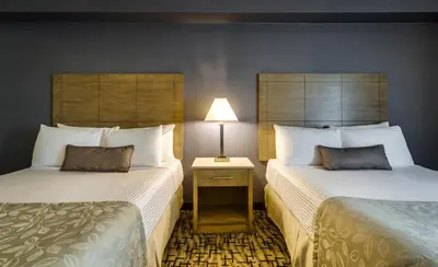a hotel room with two beds and a lamp at Monte Carlo Inn Oakville Suites in Oakville