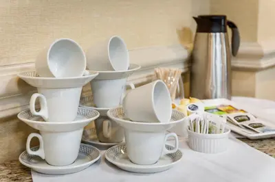 a group of white cups and saucers on a counter at Monte Carlo Inn Brampton in Brampton