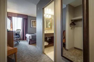 a hotel room with a mirror and a bedroom at Monte Carlo Inn Airport Suites in Mississauga