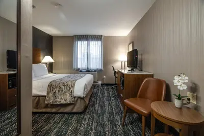 a hotel room with a bed and a table and chairs at Monte Carlo Inn Toronto West Suites in Mississauga