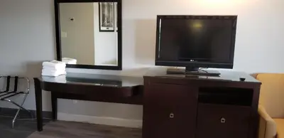 a television sitting on a dresser with a mirror at Niagara Falls Courtside Inn in Niagara Falls