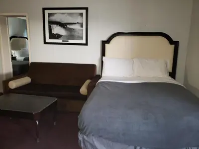 a bedroom with a bed and a couch and a chair at Niagara Falls Courtside Inn in Niagara Falls