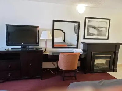 a bedroom with a desk with a television and a fireplace at Niagara Falls Courtside Inn in Niagara Falls