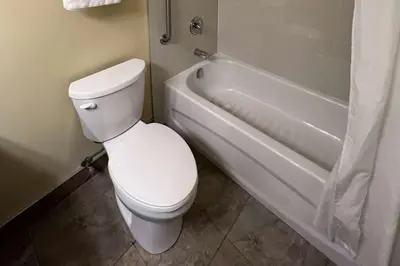 a bathroom with a white toilet and a bath tub at Ramada by Wyndham London in London