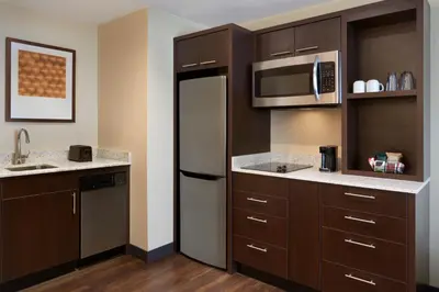 a kitchen with brown cabinets and a microwave at TownePlace Suites by Marriott Toronto Oakville in Oakville
