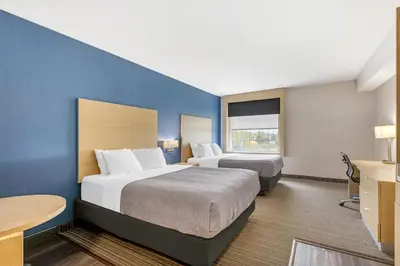 a hotel room with two beds and a blue wall at Quality Inn & Suites Oakville-Mississauga in Oakville
