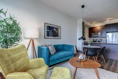 a living room with a blue couch and a table at The Benetton Suite - Square One 1 BR + Den + 1 Parking in Mississauga