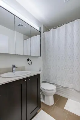 a bathroom with a toilet and a sink and a mirror at The Benetton Suite - Square One 1 BR + Den + 1 Parking in Mississauga