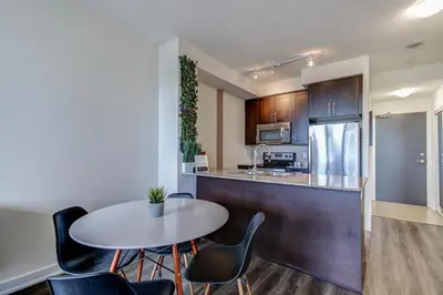 a kitchen with a table and chairs in a room at The Benetton Suite - Square One 1 BR + Den + 1 Parking in Mississauga