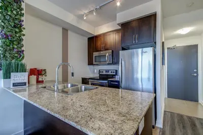a kitchen with a sink and a stainless steel refrigerator at The Benetton Suite - Square One 1 BR + Den + 1 Parking in Mississauga