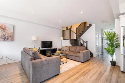 a living room with two couches and a staircase at GlobalStay Waterfront 5 Bedroom Townhouse Hot tub Sauna Stoney Creek in Hamilton