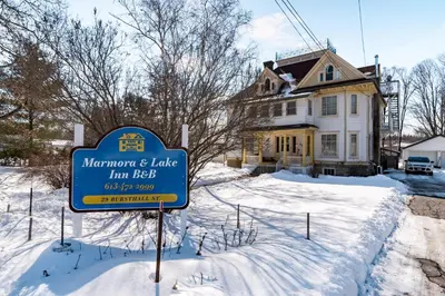 a sign in the snow in front of a house at Marmora and Lake Inn and Victorian Diner in Marmora
