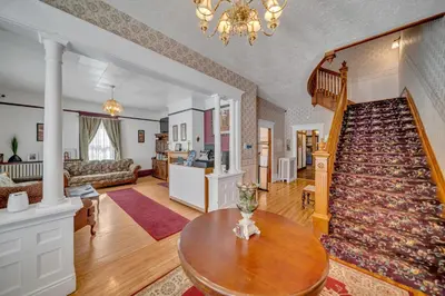 a living room with a staircase and a table at Marmora and Lake Inn and Victorian Diner in Marmora