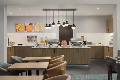 a restaurant with tables and chairs and a kitchen at Homewood Suites by Hilton Toronto-Ajax in Ajax