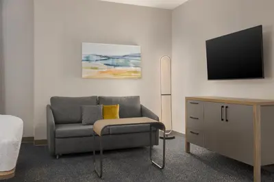 a living room with a chair and a tv at Homewood Suites by Hilton Toronto-Ajax in Ajax