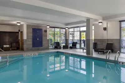 a swimming pool in a hotel with chairs and tables at Homewood Suites by Hilton Toronto-Ajax in Ajax