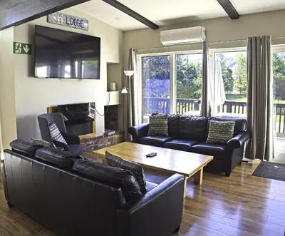 a living room with leather furniture and a table at 6BR Blue Mountain Chalet Hot Tub Updated Walk to Village Fun in Blue Mountains