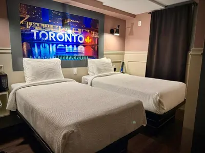 two beds in a hotel room with a painting on the wall at Royal Oak Inn in Toronto
