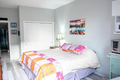 a bedroom with a white bed with a colorful blanket at The Jypsy Inn / Muskoka in Bracebridge