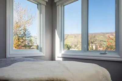 a bedroom with two large windows and a bed at Wintergreen Haven 85574 in Blue Mountains