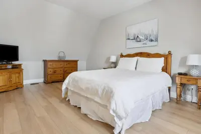 a white bedroom with a bed and a tv at 3BR Snowbridge Chalet in Blue with Golf Course View in Collingwood