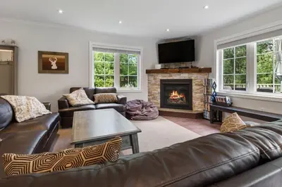 a living room with leather furniture and a fireplace at Scandia Retreat with Hot Tub, Sauna and Fire Pit in Blue Mountains