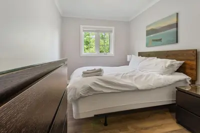 a bedroom with a large white bed and a window at Scandia Retreat with Hot Tub, Sauna and Fire Pit in Blue Mountains