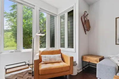 a living room with a chair and windows at Modern Mountainside Ski in Ski out 87111 in Blue Mountains