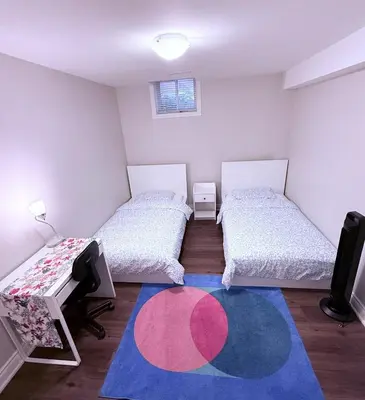 a room with two beds and a rug at Spacious basement in Mississauga