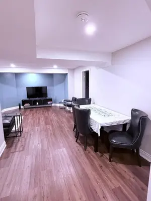 a living room with a table and chairs and a television at Spacious basement in Mississauga