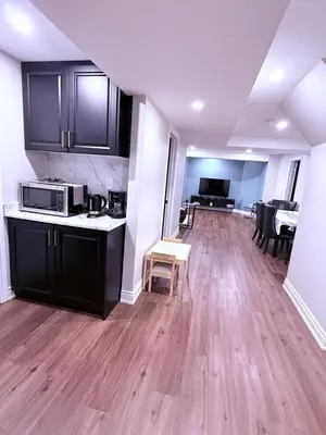 a kitchen with black cabinets and a wooden floor at Spacious basement in Mississauga