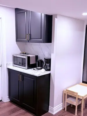 a kitchen with black cabinets and a microwave at Spacious basement in Mississauga