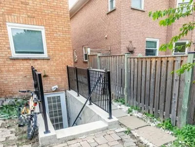 a fence in front of a brick building with a house at Spacious basement in Mississauga