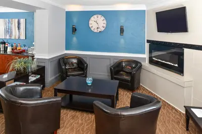 a waiting room with chairs and a table and a clock at Canadas Best Value Inn St. Catharines in St. Catharines