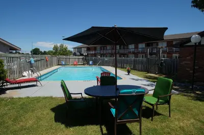 a table with chairs and an umbrella next to a pool at Canadas Best Value Inn St. Catharines in St. Catharines