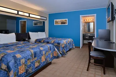 a hotel room with two beds and a desk at Canadas Best Value Inn St. Catharines in St. Catharines