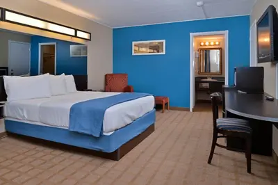 a hotel room with a bed and a desk and a computer at Canadas Best Value Inn St. Catharines in St. Catharines