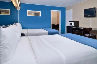 two beds in a hotel room with a blue wall at Canadas Best Value Inn St. Catharines in St. Catharines