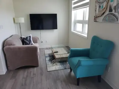 a living room with two chairs and a tv at Luxurious Condo Apartment 2BRs-1BAs-1Office with free parking in Brampton