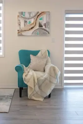 a blanket sitting on a chair in a living room at Luxurious Condo Apartment 1BR-1BA-1Office free parking in Brampton