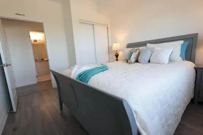 a large white bed in a room with a lamp at Luxurious Condo Apartment 1BR-1BA-1Office free parking in Brampton
