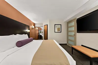 a hotel room with a large bed and a chair at Best Western Plus Toronto North York Hotel & Suites in Toronto