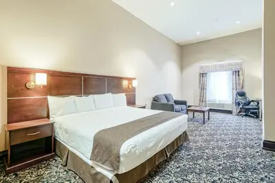 a hotel room with a large bed and a chair at Woodbine Hotel & Suites in Toronto