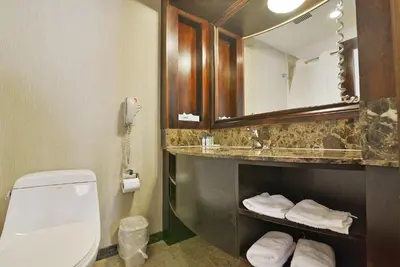 a bathroom with a toilet and a sink with a mirror at Woodbine Hotel & Suites in Toronto
