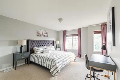 a bedroom with a bed and a desk and windows at GlobalStay 3 Bedroom Townhome with Hot Tub Hamilton in Hamilton