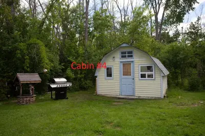 a small shed in a yard with a grill at Fun Place with a Sandy Beach for Swimming, Boating & Fishing, Featuring 1 House and 3 Cabins in Fenelon Falls