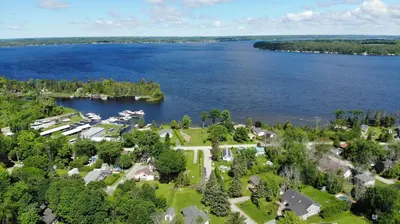 an aerial view of a house next to a lake at Fun Place with a Sandy Beach for Swimming, Boating & Fishing, Featuring 1 House and 3 Cabins in Fenelon Falls