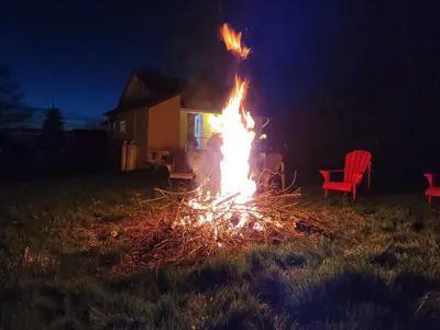 a fire in a yard at night with a red chair at Fun Place with a Sandy Beach for Swimming, Boating & Fishing, Featuring 1 House and 3 Cabins in Fenelon Falls