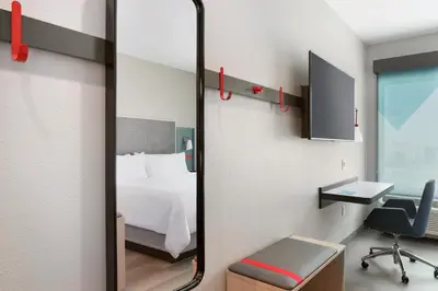 a mirror in a room with a bed and a desk at avid Hotel - Toronto - Vaughan Southwest by IHG in Vaughan