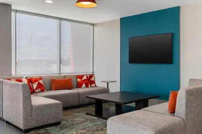 a living room with a couch and a tv on a wall at avid Hotel - Toronto - Vaughan Southwest by IHG in Vaughan